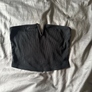 Svart tubtopp - En svart tubtopp i ribbat material. Toppen har en enkel design med en liten v-formad detalj framtill.