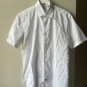 Esprit kortärmad skjorta (39/40) vit - Vit kortärmad Esprit skjorta. Strl 39/40 (S/M) Slim Fit. Oanvänd. Svart knapp nertill. Ordinariepris 549kr