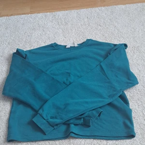 Volang tröja  - En söt grön tröja med volang på axlarna kommer inte till använding mer, inga defekter 