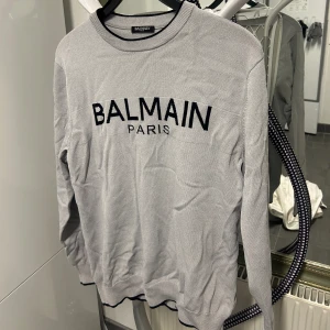 Balmain tröja (medium) - En grå Balmain Paris tröja i storlek Medium. Köpt i Dubai mall för ca 2 år sedan. Använd ungefär 6 gånger. Skrynklig från att ha legat i garderoben, annars är skicket 9/10!  Köpt för ca 4500kr