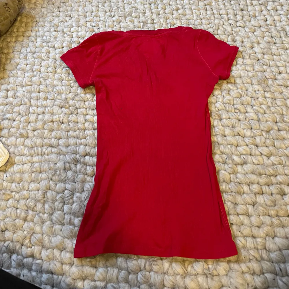 Röd ribbad åtsittande t-shirt från Hilfiger. Strl xs-m då den är väldigt stretchig och mjuk. Två egna knapphål är gjorda men syns knappt.. T-shirts.