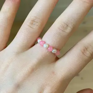 Handgjord ring med fina rosa och vita pärlor i lekfull och somrig stil🌴🌺☀️ •Gjord med silvrig ståltråd.  •Storlek 6 (ca 16mm).  •Frakt ingår i priset! Perfekt för dig som vill lägga till en fin liten touch på en outfit eller i present! 🌟