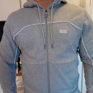 Boss hoodie  - Ljus grå hugo boss hooie zip, skicket är mycket bra inga skador eller hål och fläckar. Priset 550kr kan diskuteras kolla mina andra annonser, nästan bara nya kläder parfymer skor bälte