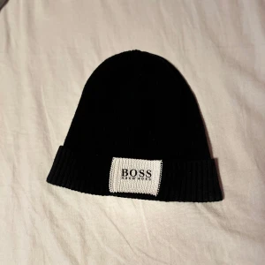 Hugo boss mössa svart  - Hugo boss mössa svart använd kanske 3 gånger för den var inte min smak av mössa, det är en onesize så passar alla nästintill. Skriv vid funderingar:)