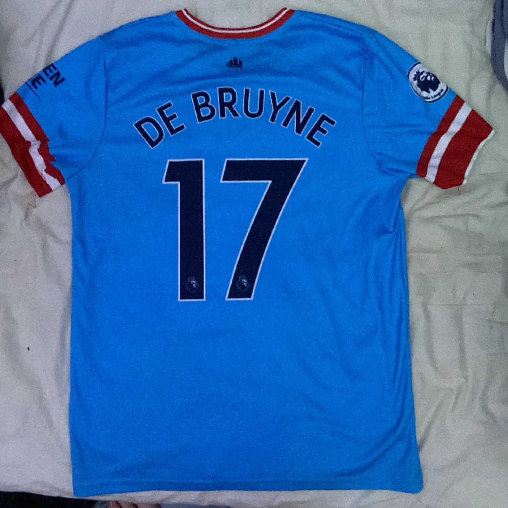Säljer en Manchester City tröja med Kevin De Bruyne på ryggen, den är fake så den är billig, Den är lite sönder på en av arm delarna.. T-shirts.