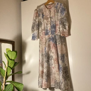 Blommig finklänning i äldre stil - Vilket vintage fynd den här klänningen är! Underbart romantisk i en stil som på senare år har gått och blivit modern igjen. Nästan som att någon har gjort akvarell-målerier på detta lätta, mesh-liknande tyget. Tjockt nog att inte vara genomskinnlig. 