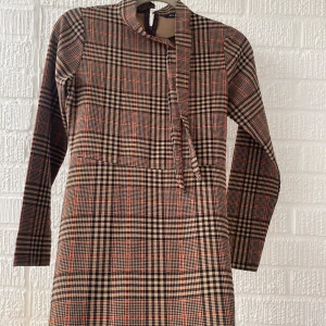 Brun kvadratig klänning - Jag vill sälja denhära jettfina bruna, kvadratiga klänningen. Den är lite svart och röd. Den har bara några lösa trådar som går att klippa av. Pris går att diskuteras!