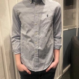 Polo raulph lauren skjorta  - Jag säljer en polo raulph lauren skjorta för 12 år 146-152 cm den har bara använts ett par gånger vid fina tillfällen 