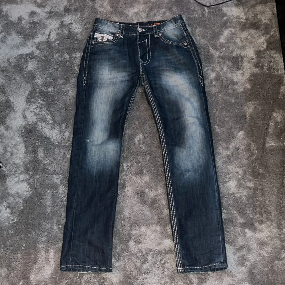 Tvär feta jeans med riktigt tuff fade, storlek W 33 L 32. Byxorna är ifrån rock revival å har massa tuffa detaljer. White stitch och feta knappar och mer. Byxorna är använda så har lite brister. Skriv för bilder på bristerna. . Jeans & Byxor.