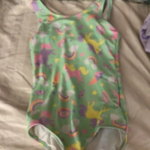 Badkläder  - Det här är badkläder till unga flickor. Den e öppen bakom lite mellan nacken och uppe vid ryggen.🙂🙂den e precis som andra badkläder 
