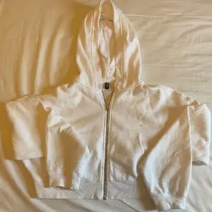 Säljer en vit Croppad zip up hoodie. Den har inga fläckar och är i bra skick. Den är i storlek L så den är lite oversize. Säljer den för har ingen användning för den. 