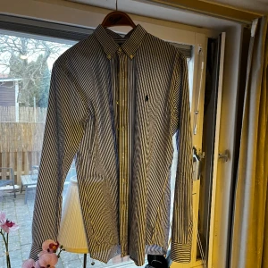 Polo Ralph lauren skjorta vit blå randig - Säljer nu denna Ralph lauren skjortan i storlek M då den är för liten. Det är en slim fit model i fint skick. Tappat lite färg sedan jag köpte den, men annars är den felfri. Den är lite stretchig i materialet, och grymt skön fit. Hörs på dm:)