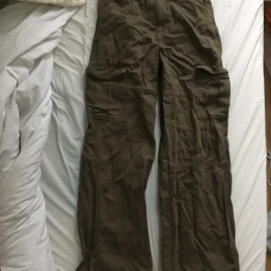 Cargo byxor - Säljer cargo byxor som inte kommer till användning de ser bruna ut på bilden men de är gröna. Jag har lagat så att det går att spänna i midjan men det går att ta bort om man vill. Läs bion före du köper!