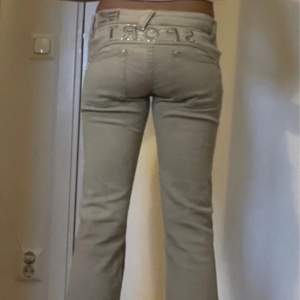 Beiga lågmidjade bootcut jeans med coola detaljer! Måtten är: Midjemått: 37cm Innerbenslängd: 76cm Längd tvärs över: 98cm Använd gärna köp nu!💘🔥😽