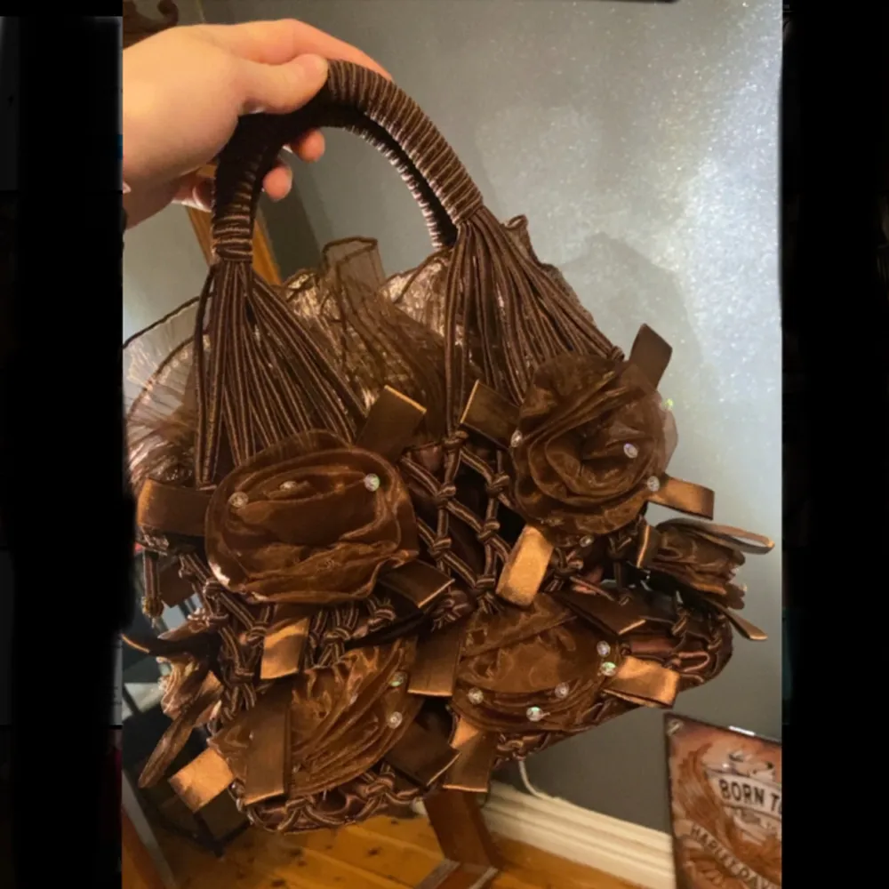 En brun gullig väska med blommor på. Väskor.