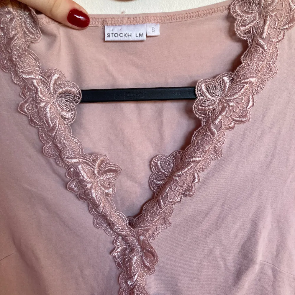 Urringad med spetsblommor, figursydd i superskönt material. Skulle säga att den är mer rosa i verkligheten. . Puserot.