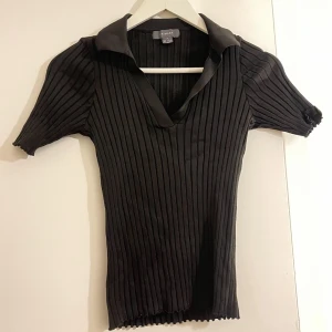 Svart tröja  - En svart, kostym aktig tröja med fina detaljer mot brösten och vikt krage. Köpt från Spanien använt några gånger. Frakt ingår med 29kr. 