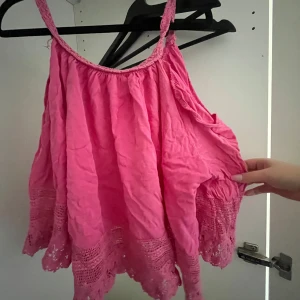 Rosa ärmlös topp med spetsdetaljer - Säljer en söt rosa unik ärmlös topp med vackra spetsdetaljer längs nederkanten. Använd fåtal gånger 