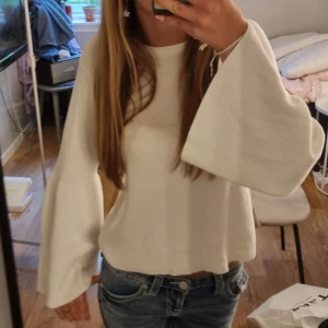 Vit långärmad tröja - Säljer en vit stickad tröja med vida ärmar. Den har en typ av öppenrygg med v ringning och man kan ha töjan pt båda hållen, som ni ser skillnad mellan bild 1 o 2, jätteskön o jättesöt💕💕 den är vintage från nelly !