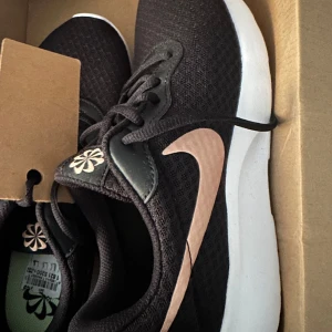 Svarta sneakers från Nike - Aldrig andvänt dem. Snygga svarta sneakers från Nike med en vit sula och en roséguldfärgad swoosh. Skorna funkar till gymet eller under en vanlig vardag.