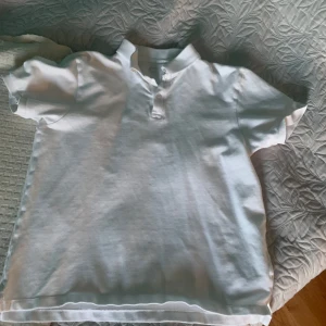 Vit kortärmad pikétröja - Säljer en klassisk vit kortärmad pikétröja med krage och knappar framtill. Perfekt för en stilren och avslappnad look. Passar bra till både jeans och shorts. 🕶️