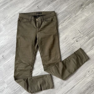 Olivgröna push up jeans från Stradivarius 36 - Snygga olivgröna byxor från Stradivarius i en smickrande slim fit med push-up effekt. Byxorna har en klassisk femficksdesign och stängs med knapp och dragkedja. Perfekta för en stilren look.