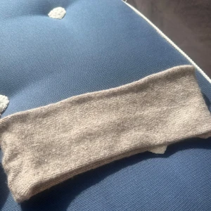 Beige kashmir pannband - Säljer ett enkelt och stilrent beige/brunt 100% kashmir pannband. Perfekt för att hålla värmen under kyliga dagar. Passar bra till både vardag och utomhusaktiviteter.