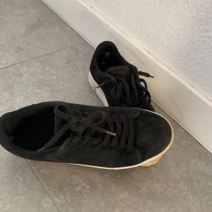 Svarta sneakers från Selected Homme - Snygga svarta sneakers från Selected Homme i storlek 41. Skorna har en klassisk design med snörning och en vit sula som ger en stilren kontrast. Perfekta för en avslappnad look.