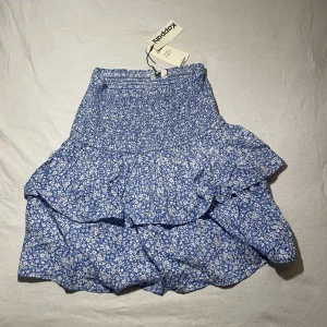 Blå blommig kjol från Kappahl - Säljer denna jättefina blå blommiga kjol från Kappahl med volangdetaljer. prislapp finns kvar.