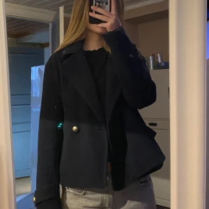 Mörkblå kavaj från Zara - Snygg mörkblå kavaj från Zara med dubbelknäppning och guldknappar. Jackans insida har vissa defekter men inget som syns med jackan på! 