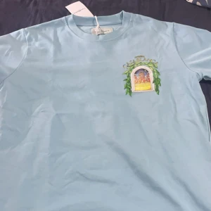 Ljusblå t-shirt med tryck från Casablanca - Säljer en snygg ljusblå Casablanca T-shirt i toppskick! Endast använd två gånger och sedan förvarad i garderoben