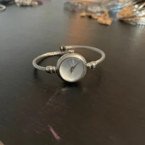 Elegant armbandsur med stålarmband - Snygg och stilren klocka med ett smalt stålarmband och en rund urtavla. Klockan har en minimalistisk design med en vit urtavla och silverdetaljer. Perfekt för att ge en touch av elegans till din outfit.