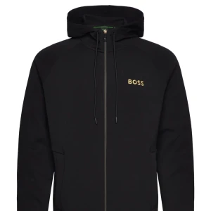Boss kofta - Säljer en stilren svart hoodie från Boss med dragkedja och justerbar huva. Den har en diskret logga på bröstet och är perfekt för en avslappnad look. Passar bra till både jeans och joggers.