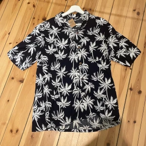 Svartvit Hawaii-skjorta - Oanvänd svartvit hawaii-skjorta. Tveka inte på att skriva