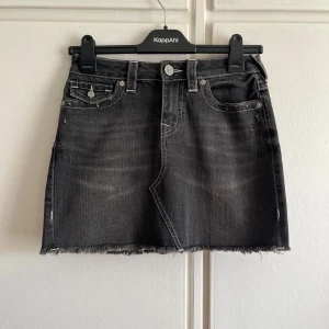 Svart jeanskjol från True Religion - Fin kjol från true religion, köpt på Raglady förra året nästan aldrig använd och som ny. Säljs för att den är lite för liten för mig. Storlek 26! 750kr eller bud:)