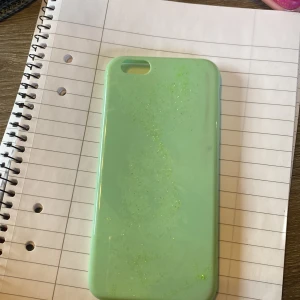 Grönt mobilskal - Säljer ett snyggt grönt mobilskal med en glittrig yta. Skalet är gjort av ett flexibelt material som skyddar din telefon samtidigt som det ger en fräsch look. Perfekt för att ge din mobil en personlig touch!