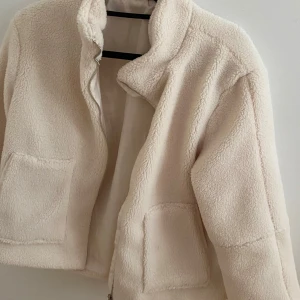 Beige teddyjacka med dragkedja - Mysig beige teddyjacka med dragkedja och två framfickor. Jackan har en normal passform och är långärmad. Nästan aldrig använd!