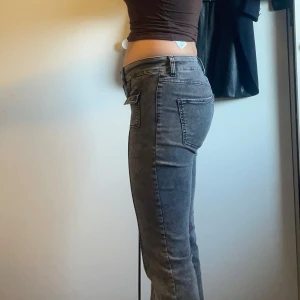 Grå jeans från Nelly - Snygga grå jeans från Nelly med låg midja och bootcut-stil. Byxorna har praktiska fickor och är tillverkade i en stretchig bomullsblandning för extra komfort. Perfekta för en avslappnad look.