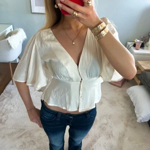 Vit blus  - Säljer en trendig och elegant krämvit blus med v-ringning och knappar framtill. Blusen har korta, vida ärmar som ger en luftig känsla. Perfekt nu till sommaren🌸storlek xs från forever 21