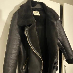 Svart skinnjacka med pälsfoder - Snygg svart skinnjacka med mjukt pälsfoder och dragkedja framtill. Jackan har en klassisk design med bred krage och långa ärmar. Perfekt för kyligare dagar. Ifrån Zara och den är i storlek m.  Inga skador eller liknande, hör av er vid funderingar!