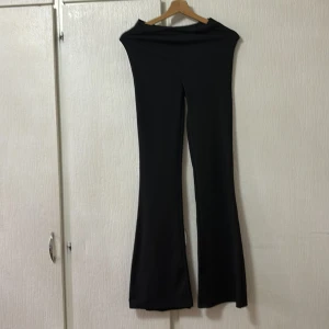 Svarta ribbade byxor - Snygga svarta ribbade byxor med en bootcut-stil. Perfekta för en stilren look. Byxorna har en hög midja och är tillverkade i ett stretchigt material för extra komfort.