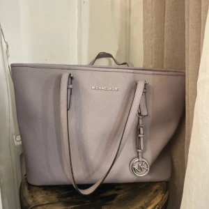  Michael Kors väska  - Säljer min fina Micheal kors väska! Den har några fläckar på insidan och är lite sliten på ena handtaget, men annars jättefint skick. Den är grå/ ljus lila 💜 