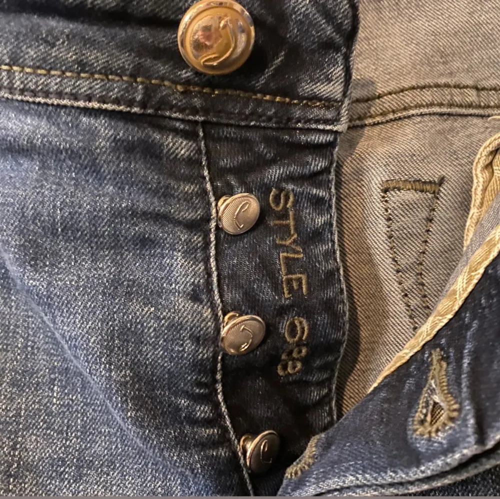 Snygga blå jeans från Jacob Cohen med knappgylf och klassisk femficksdesign. Jeansen har en stilren look med lätt slitna detaljer och en bekväm passform. Nypris 5000. Farkut & Housut.