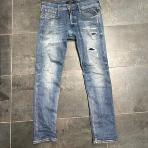 Replay Anbass ljusblå jeans, stl 32 - Säljer ett par Replay Anbass jeans i ljusblå tvätt med slitna detaljer och snygga skavda partier. Perfekt för dig som gillar en modern och avslappnad look. Hör av dig vid frågor. Pris kan diskuteras