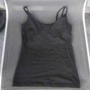 Svart linnetopp från 157 i XS - Svart linnetopp från 157 med smala justerbara axelband. Toppen är enkel och stilren med rak passform, tillverkad i mjuk bomull med lite stretch för extra komfort. Perfekt att matcha med jeans eller shorts för en chill look.