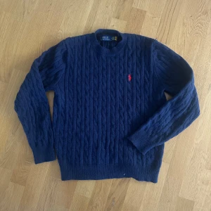 Marinblå ralph lauren stickad tröja - Säljer denna stickade tröjan/cable knit från ralph lauren. Säljs då den inte används mer. Använts fåtals gånger i vintras. Storlek S. (Säljer även en grå med etikett, kolla profil. Köper man båda får man lite rabatt)