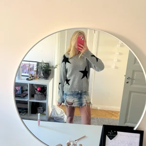 Grå stickad tröja med svarta stjärnor - Supermysig grå stickad tröja med stora svarta stjärnor på både fram- och baksida samt ärmar. Tröjan har rund hals, ribbade muddar och lång ärm. Perfekt för dig som gillar coola detaljer och vill ha en chill look.