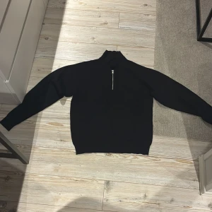 Svart pikétröja med dragkedja Jack & Jones - Svart pikétröja från Jack & Jones med klassisk krage och silverfärgad dragkedja framtill. Tröjan har långärmad passform och är tillverkad i mjuk bomull som känns skön mot huden. Perfekt för dig som gillar stilrena och enkla plagg med en modern twist. Helt omvänd.