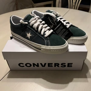 Converse One Star x thisisneverthat (collab) - Converse One Star i samarbete med thisisneverthat. Sneakers i mörkgrön färg med vit stjärna på sidan, vita snören och vit sula med svart rand, ingår även gröna snören om man vill byta. Ovandel i canvas och mocka. Helt splitternya! Aldrig använda! Nypris: 850kr