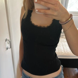 Svart linnetopp med spetskant - Snygg svart linnetopp med spetsdetalj längs halsringningen.💖